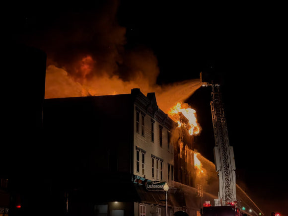 Fireman on ladder hosing down a large building fire